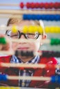 Close-up of schoolkid looking through abacus in classroom