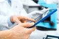 Close up of scientists hands with tablet pc in lab