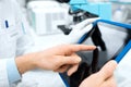 Close up of scientists hands with tablet pc in lab