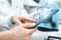 Close up of scientists hands with tablet pc in lab