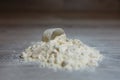 Close-up scoop in protein powder slides on a wooden table. bunch of protein powder with plastic spoon on white background. Dry mix