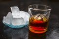 Close up of Scotch whiskey or Grain scotch in a transparent glass with ice cubes on black colored wooden surface. Royalty Free Stock Photo