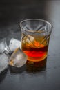 Close up of Scotch whiskey or Grain scotch in a transparent glass with ice cubes on black colored wooden surface. Royalty Free Stock Photo