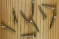 Close-up on screws, metal screws, iron screws, wood screws on wooden board Royalty Free Stock Photo