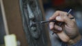 Close-up of Sculptor creating sculpture of human`s face on canvas in art studio Royalty Free Stock Photo