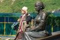 Close-up of sculpture Aksinya and blurred elderly woman on embankment of Rostov-on-Don