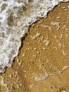 Close-up of the sea coast, clear sea water with shallow waves and a narrow strip of white foam with bubbles washes the Royalty Free Stock Photo