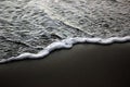 Sea foam on black sand Royalty Free Stock Photo