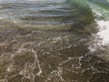 Close up of sea wave with splashes. Front view on beautiful sea wave on sandy beach. Summer sunny day, water background Royalty Free Stock Photo