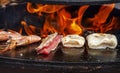 Close up seafood cuisine. Grilled fish, squid, shrimp food Hot BBQ Charcoal Grill. Flames Fire Grill Background. Outdoor