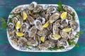 Close-up of sealed shells of fresh oysters, lemon in large plate. The concept of a picnic. Luxury seafood. green wooden