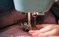 Close-up of seamstresses`s hands sews to blue jacket leather inserts on sewing mashine. Side view.