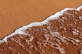 A close-up of the seashore, the surf with clear sea water washes the brown sand shore Royalty Free Stock Photo