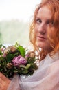 Close-up of a seductive young sexy redhead beautiful sensual woman portrait, ginger with long curly hair, outdoor with a bouquet Royalty Free Stock Photo