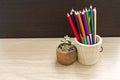 Close up seedling plant of Orange Jessamine  in pot with pencil on wooden background Royalty Free Stock Photo