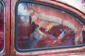 Close-up, seen through the glass of the back door: cushions on the car seat and old curtains. old red rusty damaged the car was Royalty Free Stock Photo