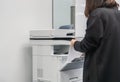 Selective focus at businesswoman in black jacket put paper sheet into office printer tray for copying business documents Royalty Free Stock Photo