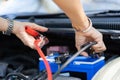 Close up and Selective focus of car mechanic holding battery electricity cables jumper for charging car battery, Services car