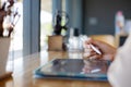 Close up and selective focus with copy space of business woman hand with stylus and using tablet to do her work on wooden counter