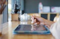 Close up and selective focus with copy space of business woman hand with stylus and using tablet to do her work on wooden counter