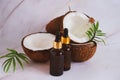 selective focus glass bottles with coconut oil on a blurred background of cracked coconuts and palm leaves Royalty Free Stock Photo