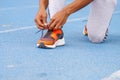 Close up of selective focus of hands and legs of young black athlete man tying running shoes in the park outdoor