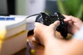 Close up Selective focus on joystick , Kid busy playing video game while books in front foreground - concept of kids gaming and