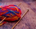 Close up of a multi coloured ball of knitting yarn and bamboo knitting needles on a wooden floor Royalty Free Stock Photo