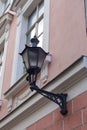 Close up, selective focus of old-style black street lamp lantern on the renewed pink building facade wall with window Royalty Free Stock Photo