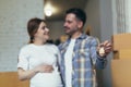 Close-up selective focus photo, man and pregnant woman together in new apartment smiling and happy holding house keys Royalty Free Stock Photo