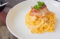Close up and selective focus shot of creamy spaghetti carbonara with grilled bacon and parsley topping served in clean white plate Royalty Free Stock Photo