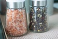 Close up and selective focus shot in perspective view with copy space of two bottle of pink salt and pepper in containers with