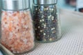 Close up and selective focus shot in perspective view with copy space of two bottle of pink salt and pepper in containers with