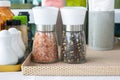 Close up and selective focus shot of two bottle of pink salt and pepper in containers with grinder prepared for restaurant