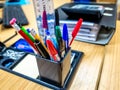 Pens, pencils and stationary in a desk tidy on a wooden table in a commercial office