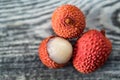 Three lychee fruits on wooden background close