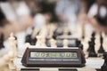 Close-up and selective focus on Time Clocks in street chess tournament surrounded by defocused chess pieces in the background.