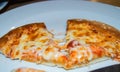 Close-up of selective focus, two pieces of hot pizza with cheese stretching on a white plate in a cafe on a wooden table Royalty Free Stock Photo