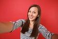 Close up selfie shot of beautiful smiling young woman in casual striped clothes isolated on bright red wall background Royalty Free Stock Photo