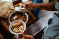 close up of seller& x27;s hand put chicken over noodles