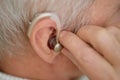 Senior Adjusting Hearing Aid With Focus on Ear Royalty Free Stock Photo