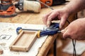 Close-up senior carpenter glueing wooden craft surface and joining with clamps. Woodwork carpenter with equipment and tools at