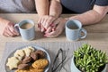 Close up of senior couple holding hands enjoying coffee and cookies Royalty Free Stock Photo