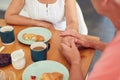 Close Up Of Senior Man Comforting Woman Suffering With Depression At Breakfast Table At Home