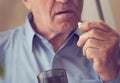 Close up of senior man taking medicine pill at home. Tinted photo Royalty Free Stock Photo