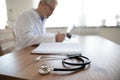 Close up senior mature doctor work desk with stethoscope Royalty Free Stock Photo