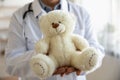 Close up senior pediatrician wearing uniform holding fluffy teddy