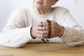 Close-up on senior person;s hands with rosary and cros