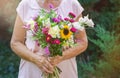 Elderly woman get a beautiful bouquet of field flowers. Senior lady holding a bunch of flowers. Royalty Free Stock Photo