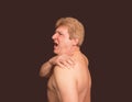 Close-up of senior shirtless man with shoulder pain over black background